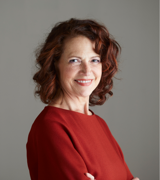 A portrait photo of a mature business woman in a red blouse smiling at the camera