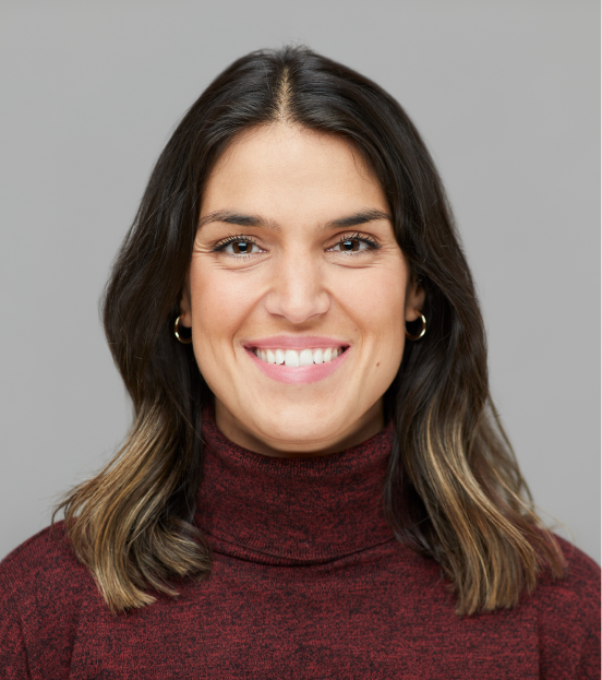 A portrait photo of a business woman in a maroon turtleneck smiling at the camera