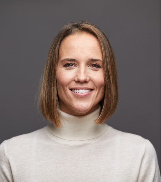 A portrait photo of a businesswoman in a cream colored turtleneck smiling at the camera