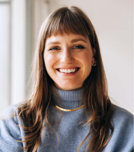 A portrait photo of a professional woman in a blue turtleneck sweater smiling at the camera