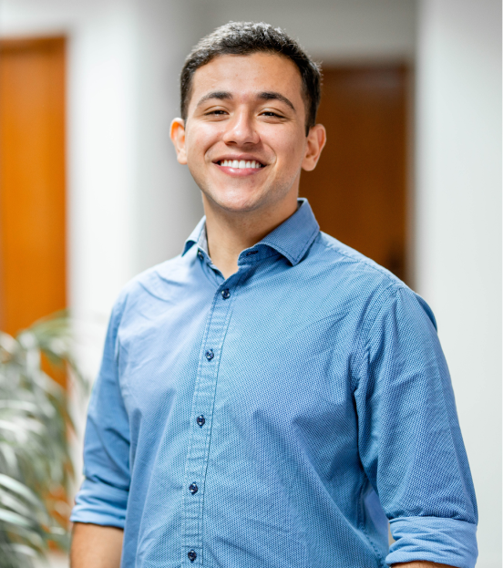 A portrait photo of a young professional male in a blue button down smiling at the camera