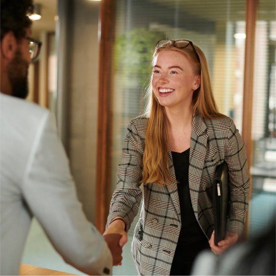 A young professional smiling and shaking the hand of a potential employer