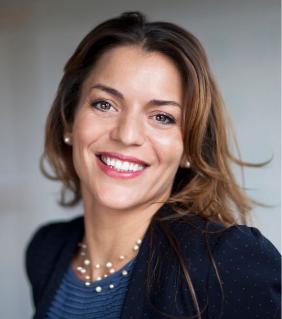 A portrait photo of a businesswoman in a blue blouse and navy blue blazer smiling at the camera