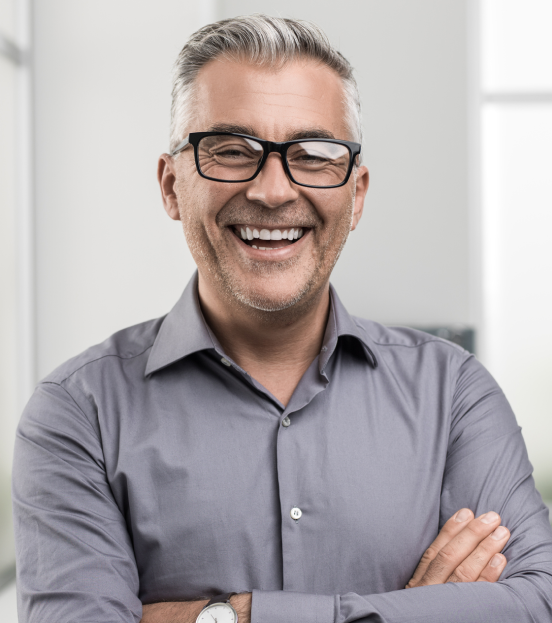 A portrait shot of a mature businessman smiling in a grey button down shirt
