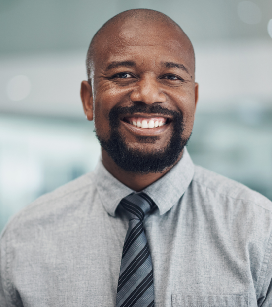 A portrait photo of a man in a grey shirt and striped tie smiling